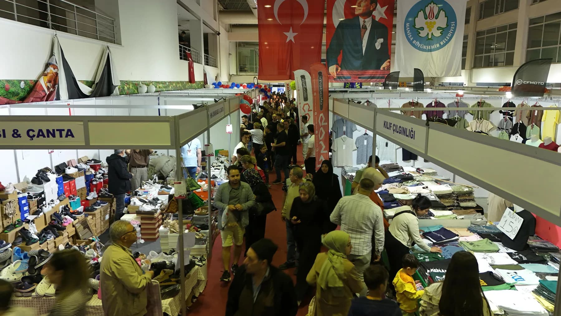 Fuar salonunun üst kattan görünümü: stantlar arasında gezen kalabalık ziyaretçi grubu